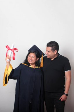 Esmer, kep ve cübbe giymiş Latin kızı ile gururlu ve tatmin olmuş bekar babası, okulun sonunu kutluyor.