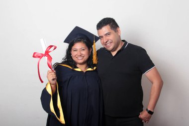 Esmer, kep ve cübbe giymiş Latin kızı ile gururlu ve tatmin olmuş bekar babası, okulun sonunu kutluyor.