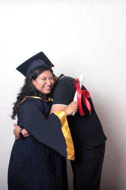 Esmer, kep ve cübbe giymiş Latin kızı ile gururlu ve tatmin olmuş bekar babası, okulun sonunu kutluyor.