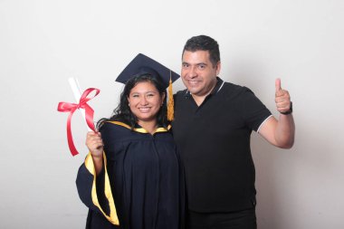 Esmer, kep ve cübbe giymiş Latin kızı ile gururlu ve tatmin olmuş bekar babası, okulun sonunu kutluyor.