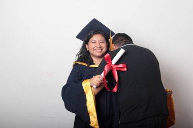 Esmer, kep ve cübbe giymiş Latin kızı ile gururlu ve tatmin olmuş bekar babası, okulun sonunu kutluyor.