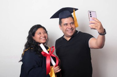 Esmer, kep ve cübbe giymiş Latin kızı ile gururlu ve tatmin olmuş bekar babası, okulun sonunu kutluyor.