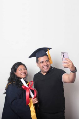 Esmer, kep ve cübbe giymiş Latin kızı ile gururlu ve tatmin olmuş bekar babası, okulun sonunu kutluyor.