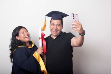 Esmer, kep ve cübbe giymiş Latin kızı ile gururlu ve tatmin olmuş bekar babası, okulun sonunu kutluyor.