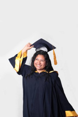 Mezuniyetini kutlamak için kep ve cübbe giyen 25 yaşında genç esmer bir kadın. Gururlu, memnun ve mutlu bir şekilde okulu bitirmiş.