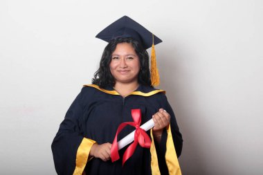 Şapka ve cübbe giymiş genç esmer kadın diplomasını gururla, tatmin olmuş ve kariyerini okulunda bitirmekten mutlu olarak gösteriyor.