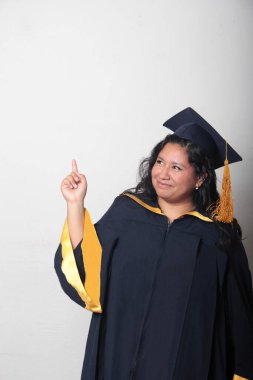 Genç esmer Latin kadın kep ve cübbe giyerek mezuniyetini ve eğitimini tamamlayışını kutluyor.