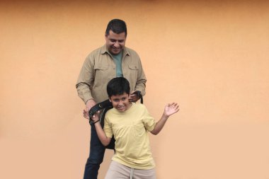 Boşanmış bekar baba, 10 yaşındaki Latin oğluna sırt çantasıyla okula dönmesi için yardım ediyor.