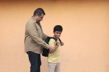 Boşanmış bekar baba, 10 yaşındaki Latin oğluna sırt çantasıyla okula dönmesi için yardım ediyor.