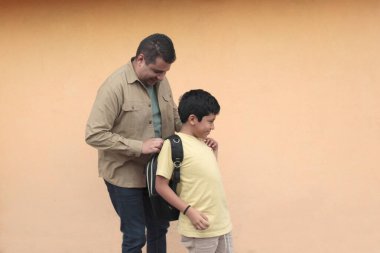 Boşanmış bekar baba, 10 yaşındaki Latin oğluna sırt çantasıyla okula dönmesi için yardım ediyor.