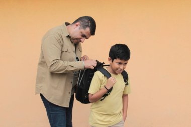 Boşanmış bekar baba, 10 yaşındaki Latin oğluna sırt çantasıyla okula dönmesi için yardım ediyor.