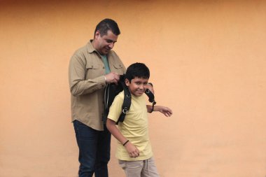 Boşanmış bekar baba, 10 yaşındaki Latin oğluna sırt çantasıyla okula dönmesi için yardım ediyor.