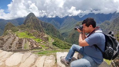 Yetişkin koyu tenli Latin fotoğrafçı Machu Picchu arkeolojik sitesinin fotoğraflarını çekiyor, dünyanın yedi harikasından biri.