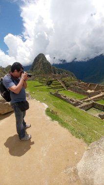 Yetişkin koyu tenli Latin fotoğrafçı Machu Picchu arkeolojik sitesinin fotoğraflarını çekiyor, dünyanın yedi harikasından biri.