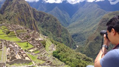 Yetişkin koyu tenli Latin fotoğrafçı Machu Picchu arkeolojik sitesinin fotoğraflarını çekiyor, dünyanın yedi harikasından biri.