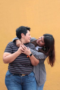 Koyu tenli iki Latin lezbiyen bir çift ve sevgilerini öpücüklerle ve kucaklaşmalarla gösteriyorlar.