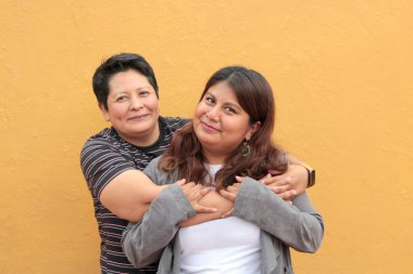 Koyu tenli iki Latin lezbiyen bir çift ve sevgilerini öpücüklerle ve kucaklaşmalarla gösteriyorlar.