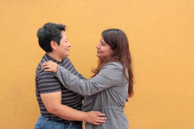 Koyu tenli iki Latin lezbiyen bir çift ve sevgilerini öpücüklerle ve kucaklaşmalarla gösteriyorlar.