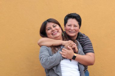 Koyu tenli iki Latin lezbiyen bir çift ve sevgilerini öpücüklerle ve kucaklaşmalarla gösteriyorlar.