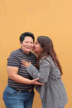 Koyu tenli iki Latin lezbiyen bir çift ve sevgilerini öpücüklerle ve kucaklaşmalarla gösteriyorlar.