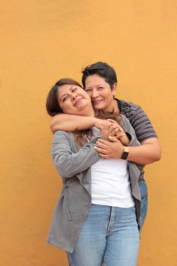 Koyu tenli iki Latin lezbiyen bir çift ve sevgilerini öpücüklerle ve kucaklaşmalarla gösteriyorlar.