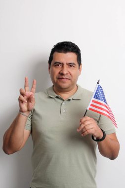 40 yaşındaki esmer tenli Latin bir adam Amerikan bayrağını gösteriyor ve vatandaşlık almak için çalışıyor.