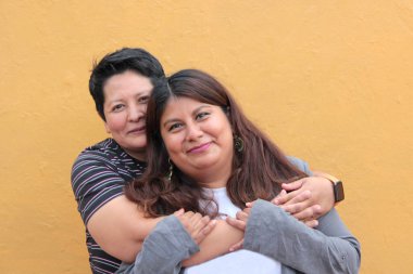 Koyu tenli iki Latin lezbiyen bir çift ve sevgilerini öpücüklerle ve kucaklaşmalarla gösteriyorlar.