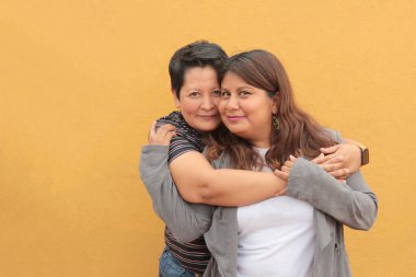 Koyu tenli iki Latin lezbiyen bir çift ve sevgilerini öpücüklerle ve kucaklaşmalarla gösteriyorlar.