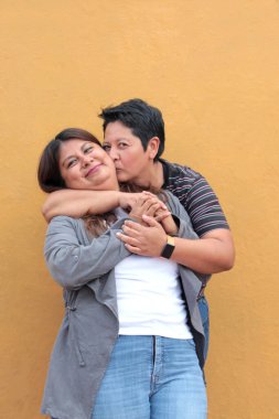 Koyu tenli iki Latin lezbiyen bir çift ve sevgilerini öpücüklerle ve kucaklaşmalarla gösteriyorlar.