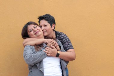 Koyu tenli iki Latin lezbiyen bir çift ve sevgilerini öpücüklerle ve kucaklaşmalarla gösteriyorlar.