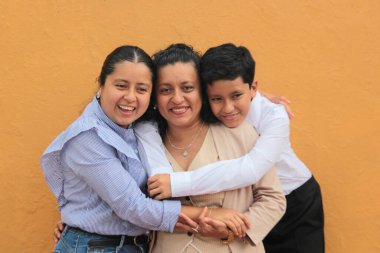 Esmer tenli Latin anne, kız ve oğul sevgilerini sarıl ve anneler gününü aileleriyle kutla.