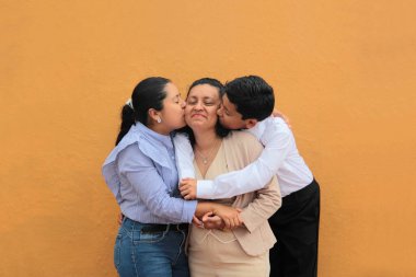 Esmer tenli Latin anne, kız ve oğul sevgilerini sarıl ve anneler gününü aileleriyle kutla.