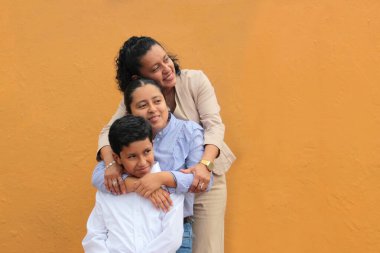 Esmer tenli Latin anne, kız ve oğul sevgilerini sarıl ve anneler gününü aileleriyle kutla.