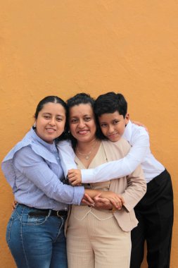 Esmer tenli Latin anne, kız ve oğul sevgilerini sarıl ve anneler gününü aileleriyle kutla.