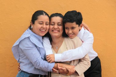 Esmer tenli Latin anne, kız ve oğul sevgilerini sarıl ve anneler gününü aileleriyle kutla.