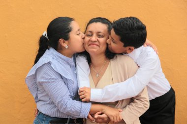 Esmer tenli Latin anne, kız ve oğul sevgilerini sarıl ve anneler gününü aileleriyle kutla.