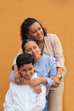 Esmer tenli Latin anne, kız ve oğul sevgilerini sarıl ve anneler gününü aileleriyle kutla.