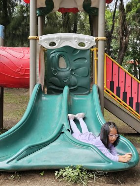 Gözlüklü 5 yaşındaki Latin esmer kız dikkat eksikliği tedavisi için sadece oyun alanındaki ekipmanlarla oynuyor.