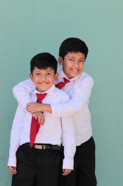 Üniforma giymiş iki koyu tenli Latin erkek sınıf arkadaşı okula döndükleri için heyecanlı ve mutlular.