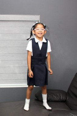 5 yaşında, Latin esmer, gözlüklü, üniformalı bir kız. Okuldan sonra oyun oynuyor ve dinleniyor.