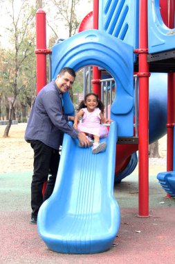 Bekar baba ve 4 yaşındaki kıvırcık saçlı Latin kızı oyun parkında oynuyorlar ve hafta sonu tatillerinde boş vakitlerini geçiriyorlar.