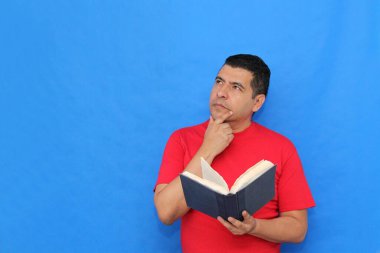 Yetişkin koyu tenli Latin bir adam, bir öğrenci ve öğretmen olarak bilgi edinmek ve öğrenmek için bir kitap okur ve gösterir.