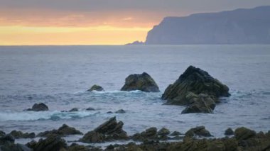 Sunrise over the sea with waves splashing on the rocky cliffs. Nature morning autumn sea background. Durness, Scotland