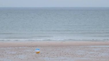 Childrens multi-coloured ball rolling in the wind on a sea beach. Scotland