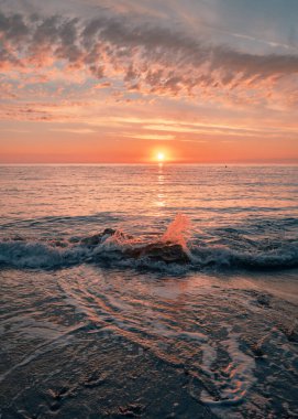 Sunrise on the seashore on the Italian Riviera. Splashing waves illuminated by sunlight. Vacation travel holiday banner, summer mood. The Ligurian Sea, Italy