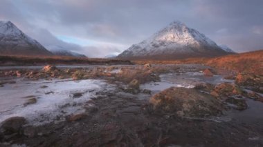 Gün doğumunda Buachaille Etive Mor Dağı ve donmuş Coe Nehri 'nin 4K görüntüleri. İskoçya İskoçya, İngiltere. 