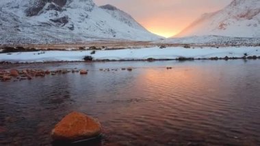 Calm river with stone on the foreground at the foot of Buachaille Etive Mor at the entrance to the valley of Glencoe in the Scottish Highlands, Scotland