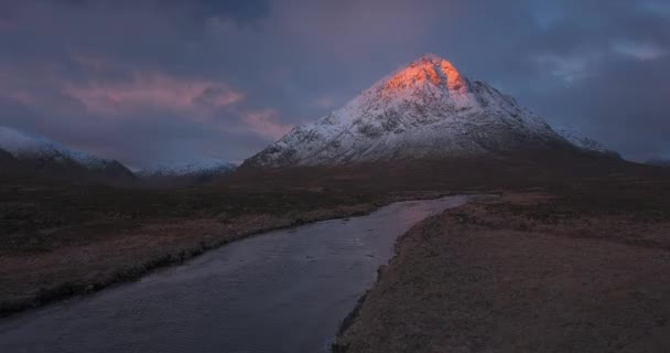 雪に覆われたBuachaille Etive Mor山と日の出のCoe川の4K映像 朝日が山頂を明るく照らしている イギリスのスコティッシュ ハイランド — ストック動画