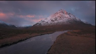 Güneş doğarken Buachaille Etive Mor Dağı ve Coe Nehri 'nin 4K görüntüleri. İleriye doğru dönüyor. İskoçya İskoçya, İngiltere. 