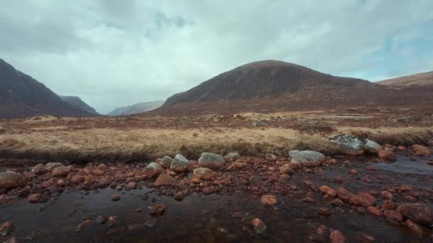バッハイル山の4K映像と前景にある岩の多いクー川 パンニングカメラの動きとビデオ イギリスのスコティッシュ ハイランド — ストック動画